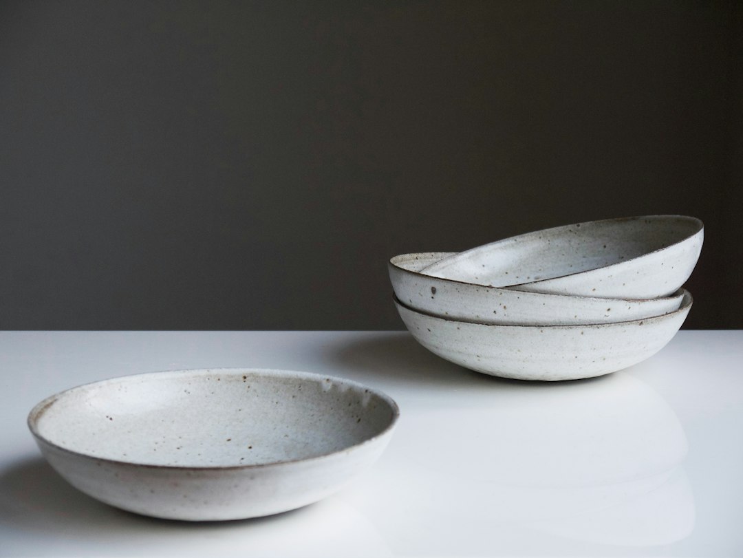 Speckled white ceramic bowls stacked on a counter, with two bowls in the foreground