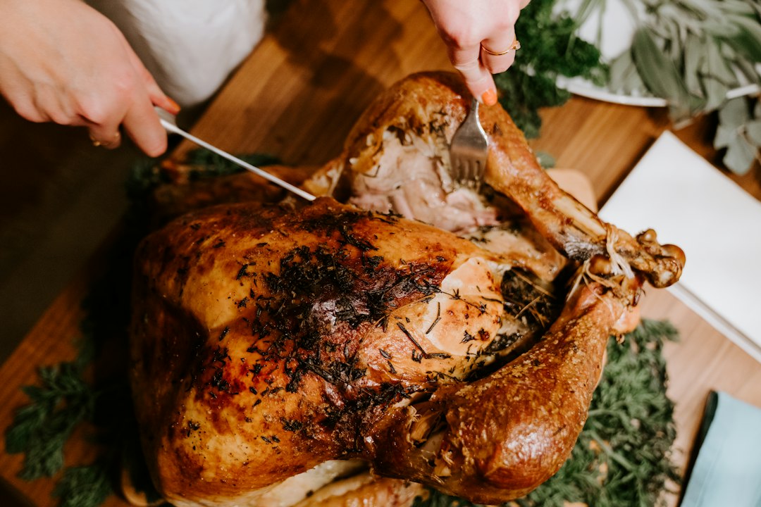Carving a golden herb-crusted roast turkey on a wooden board with a knife and fork
