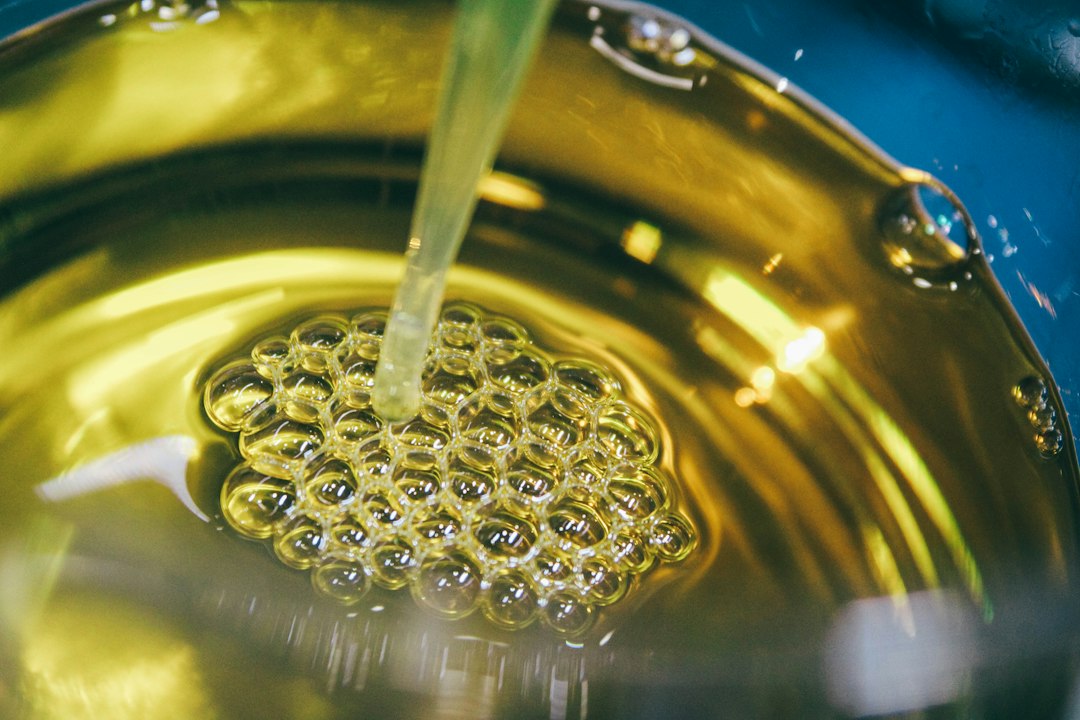 Clear golden cooking oil being poured into a pot, forming bubbles on the surface