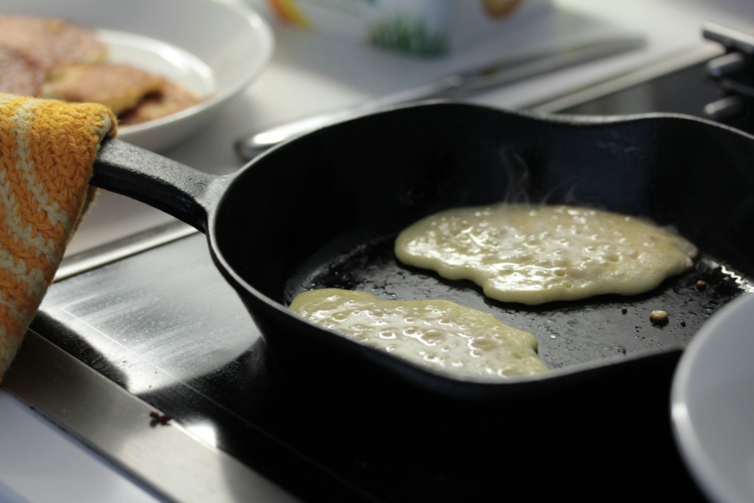 Pancakes sizzling in a seasoned black cast iron skillet on the stovetop
