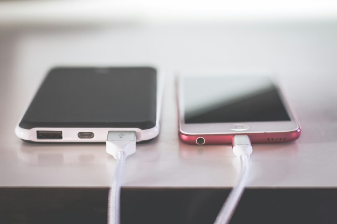Two phones resting on a counter while charging, cables neatly connected