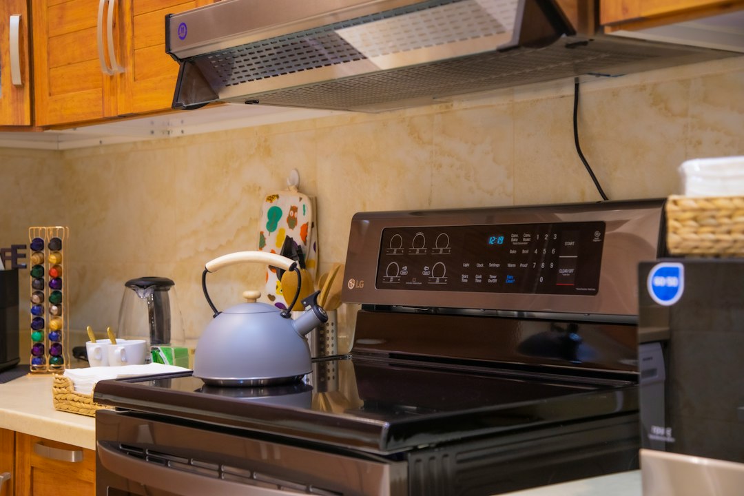 A kettle sitting on a kitchen range with the range hood above