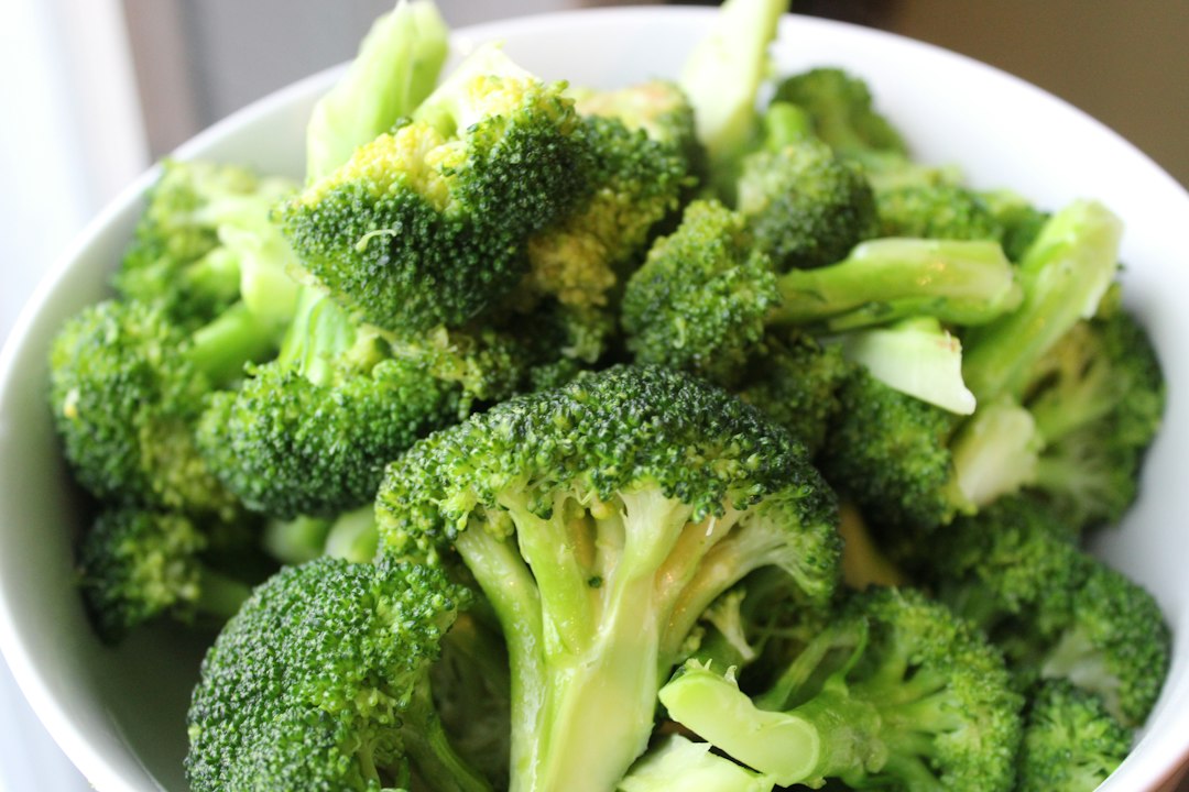 Raw broccoli florets piled in a white bowl