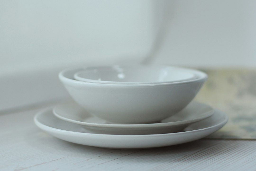 Neatly stacked white plates and bowls on a wooden surface
