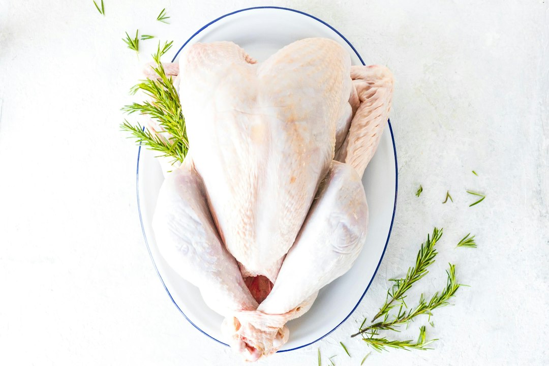 Whole raw turkey on a platter with rosemary sprigs