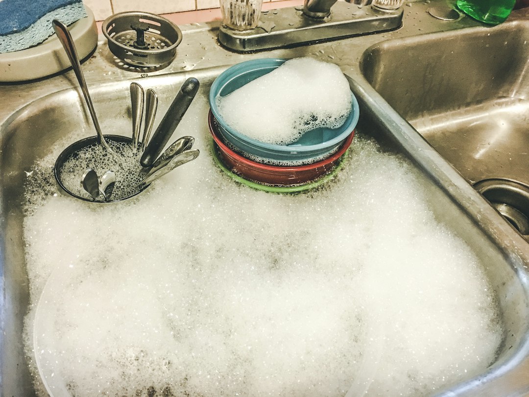 Sink full of soapy water with stacked bowls and utensils