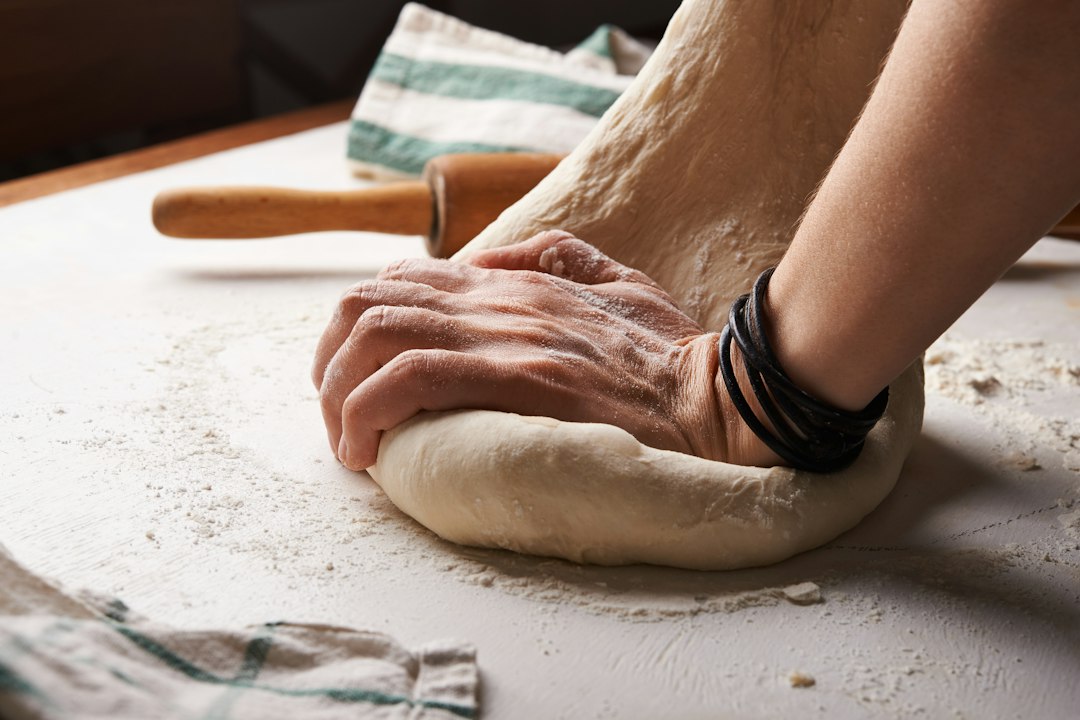 Rolling out cookie dough on a floured counter with a wooden pin