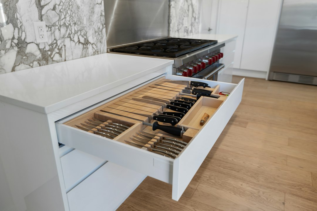 Open white kitchen drawer with knives stored in wooden slots